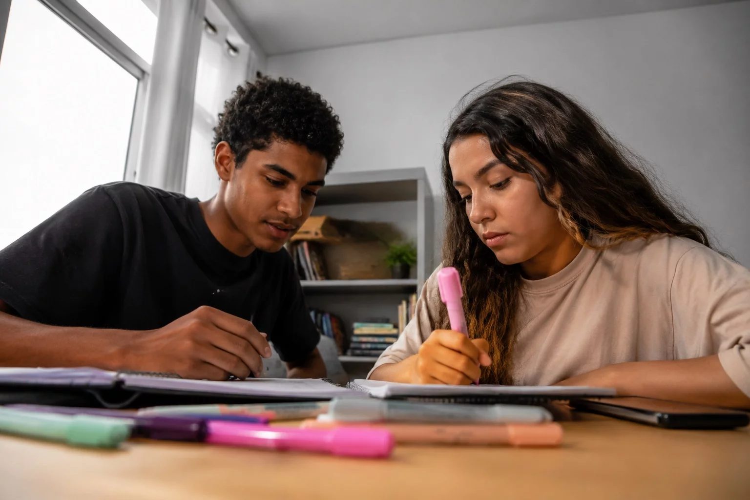 Dois estudantes preparando um debate com cadernos e marcadores